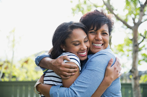 an older woman going through menopause hugs her daughter