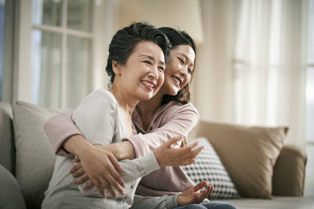 asian adult daughter and senior mother hugging each other at home
